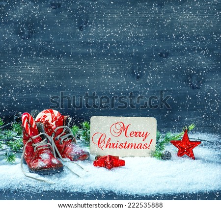 vintage christmas decoration red stars and antique baby shoes in snow over wooden background. retro style toned picture with sample text Merry Christmas!