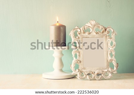 low key image of vintage antique classical frame and burning candle on wooden table