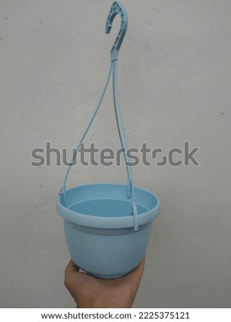 A hand holding Hanging pot of baby blue colors on a white background