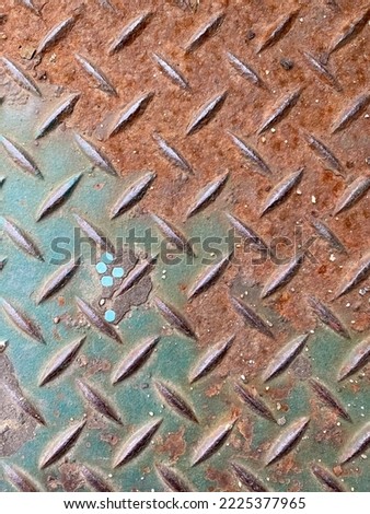 Close up of rusty diamond plate with five blue dots on it.