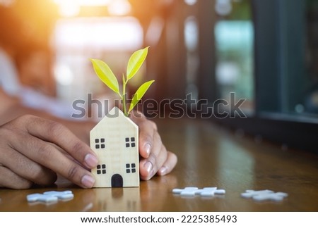 home buying idea A business man plans to take care of a wooden jigsaw house from natural materials. Puzzle in the form of a wooden house Sell ​​or rent. building eco-friendly accommodation
 Royalty-Free Stock Photo #2225385493