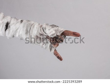 Mummy's hand in bandages shows Rock symbol on graybackground. Halloween concept
