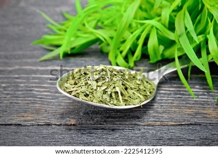Dried tarragon in a spoon, fresh estragon on the background of a wooden board Royalty-Free Stock Photo #2225412595