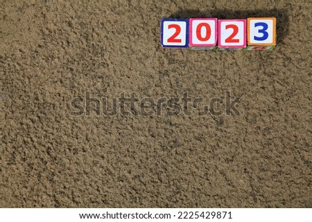 Inscription 2023. Toy square cubes and numbers on the sand on the river bank, that means coming New Year Eve. Christmas, holidays, celebration concept. New Year of 2023, year of black water rabbit