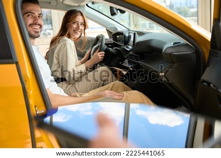 Happy couple sitting in new car in showroom