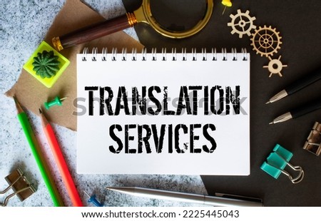 On a wooden table there are reports, a potted plant, a magnifying glass, a black pen and a notebook with the text TRANSLATION SERVICES. Business concept