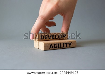 Develop agility symbol. Concept word Develop agility on wooden blocks. Businessman hand. Beautiful grey background. Business and Develop agility concept. Copy space