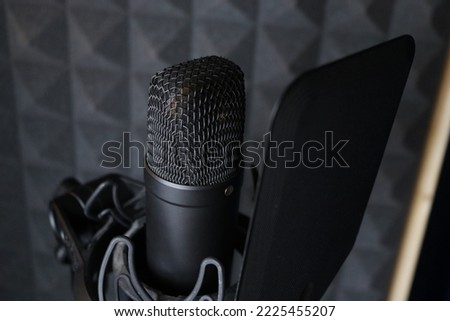 Black condenser microphone in the recording studio. Soundproofing foam in background 