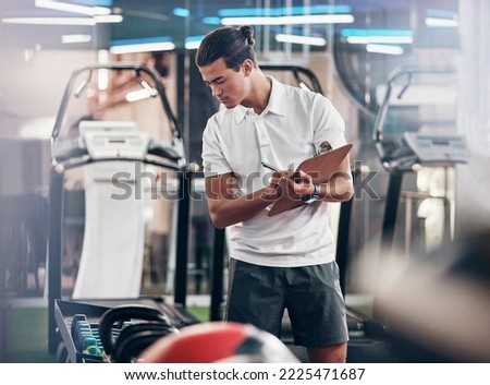 Gym, coach and clipboard with a man manager checking equipment in the gym and writing notes. Leader, personal trainer and athletic male checking exercise weights in a healthclub to prepare Royalty-Free Stock Photo #2225471687