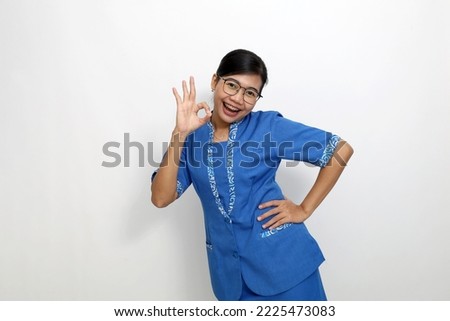 Cheerful young asian woman standing while showing okay hand gesture. Isolated on white background