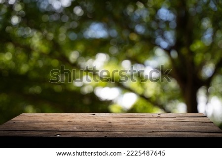 Empty wooden board on table top and blur inside abstract green background with natural bokeh, mock up for display of goods.