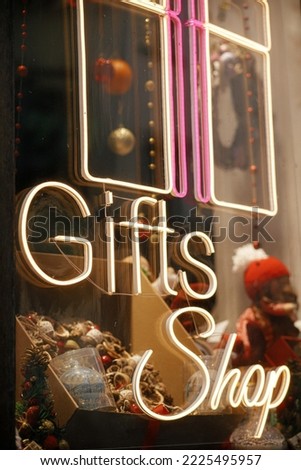 Stylish Christmas neon sign gift shop on building exterior. Modern christmas decor in city street. Winter holidays in Europe. Merry Christmas