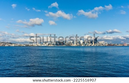 Architecture of the Seattle skyline with Elliott Bay in front and clouds above.
