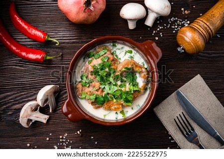 Healthy chicken stew of chicken breasts stewed in sauce served on a rustic clay pot on a dark wooden background. Georgian food chicken fillet stewed in walnut sauce on a bowl. Top view. Royalty-Free Stock Photo #2225522975