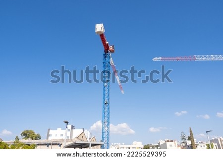 A tall tower crane rises above low-rise buildings. Preparation of a construction site for the construction of a high-rise building.