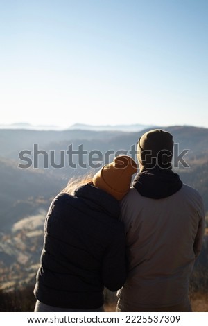 Young couple from behind enjoying fall mountains landscape in the morning