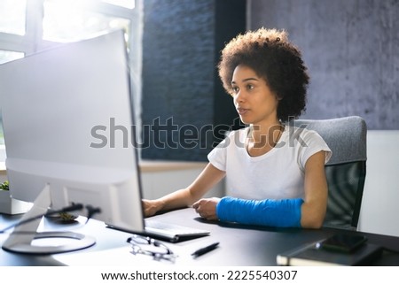 Injured Worker Compensation. Broken Arm African Woman On Computer Royalty-Free Stock Photo #2225540307