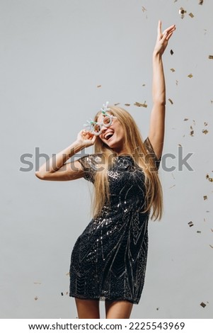 A beautiful blonde girl is dancing under glittering confetti. New Year party concept.