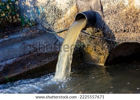 Wastewater sewage pipe dumps the dirty contaminated water into the river. Water pollution, environment contamination concept Royalty-Free Stock Photo #2225557671