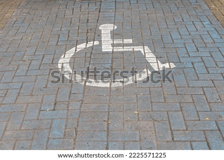 Sign painted handicapped parking spot, blue square on paving stone
