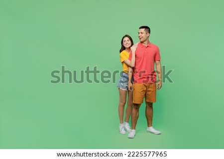 Full body smiling happy cool young couple two friends family man woman wear basic t-shirts together look aside on workspace area mock up isolated on pastel plain light green background studio portrait