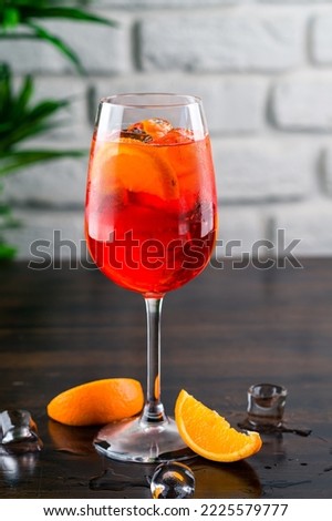Shining cocktail Aperol syringe in a wine glass with ice and a slice of orange on a dark background, cocktail aperol syringe with orange