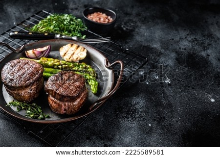 Grilled Fillet Mignon Steak with roasted asparagus. Black background. Top view. Copy space. Royalty-Free Stock Photo #2225589581