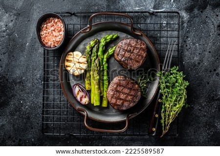 Grilled Fillet Mignon Steak with roasted asparagus. Black background. Top view. Royalty-Free Stock Photo #2225589587