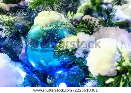 Closeup of Festively Decorated Outdoor Christmas tree with bright red balls on blurred sparkling fairy background. Defocused garland lights, Bokeh effect. The snowstorm.