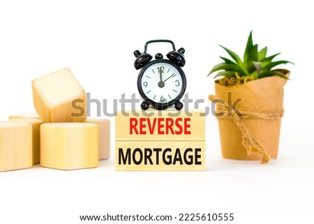 Reverse mortgage symbol. Concept words Reverse mortgage on wooden blocks. Beautiful white table white background. Black alarm clock. Business and reverse mortgage concept. Copy space.