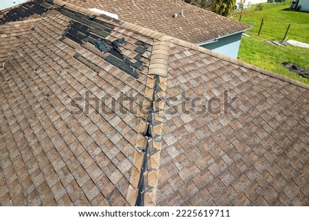 Damaged house roof with missing shingles after hurricane Ian in Florida. Consequences of natural disaster Royalty-Free Stock Photo #2225619711