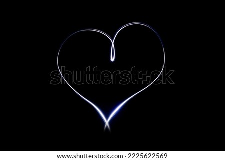 Light heart symbol on isloted black background. Long exposure creative photography. Light painting. Love and romance emblem. Glowing and bright effect.