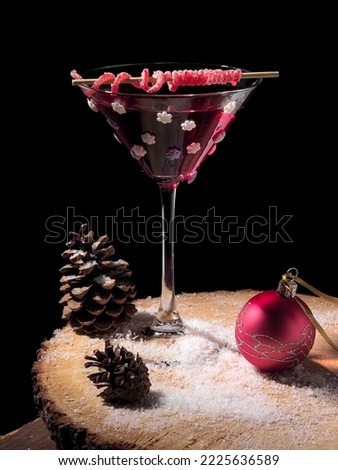 Christmas red martini cocktail with snowflakes and red jelly candy decoration on wood on black background