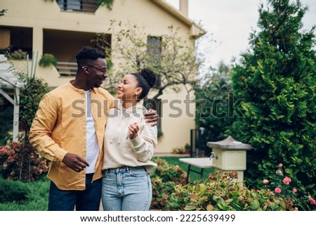 Portrait of a diverse couple holding keys and standing outside their new home on a moving day and looking at each other. Multiracial people outside their new house. Copy space. Investing in property. Royalty-Free Stock Photo #2225639499