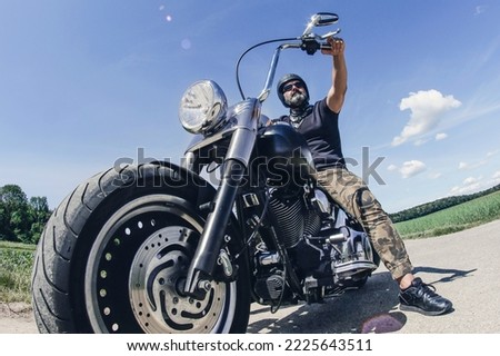 biker on a black motorcycle with beard and helmet, fisheye lens Royalty-Free Stock Photo #2225643511
