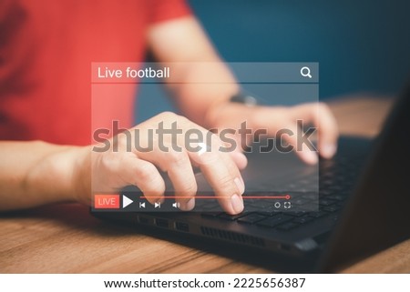 Man using a computer laptop for watching live football streaming online on virtual screen, searching video on internet, concept of content online.