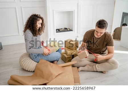 Couple man and woman prepare presents for holiday caucasian male and female packing gifts for friends using wrap paper happy smile hold gift box at home real people copy space