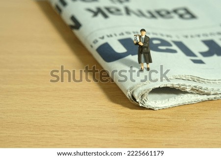 Miniature people toy figure photography. A woman holding photo frame, searching missing person because of war conflict above newspaper. Image photo