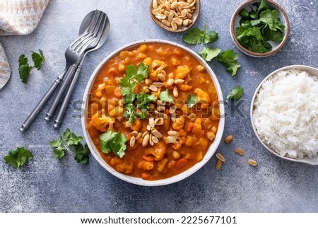Vegan curry with cauliflower, chickpeas and butternut squash topped with peanuts, served with rice and cilantro Royalty-Free Stock Photo #2225677101