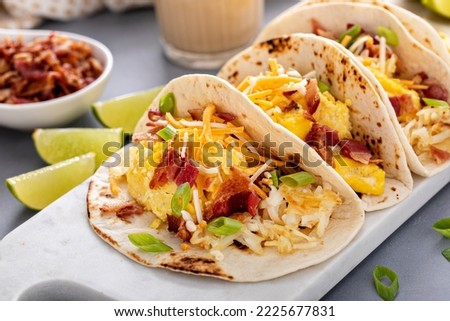 Breakfast tacos with hashbrowns, scrambled eggs and bacon topped with cheese and green onion Royalty-Free Stock Photo #2225677831