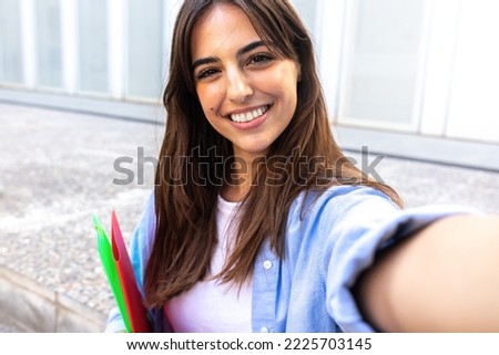 Young female caucasian college student taking selfie looking at camera.