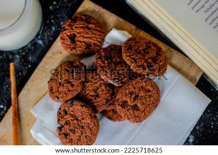 Chocolate biscuits served on a wooden cutting board. Nutritional snack, dessert or breakfast meal. Black background. Close-up of food. Cake with chocolate raisins.