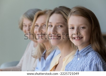 Close up faces in row, diverse women smile looking at camera, little cute girl, her adult mother, mature grandmother and old great-grandmother portraits. Multi-generational family, heredity, offspring Royalty-Free Stock Photo #2225721049
