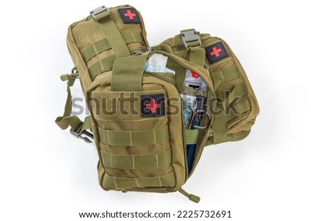 Partly open equipped military individual first aid kit in the textile pouch, the same closed kits on a white background
