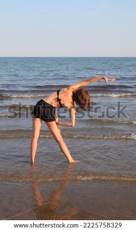 slim athletic girl performs gymnastic exercises  in summer