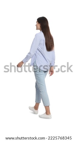Young woman in stylish outfit walking on white background