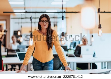 Female boss, manager executive posing in a modern startup office while being surrounded by her coworkers, team.