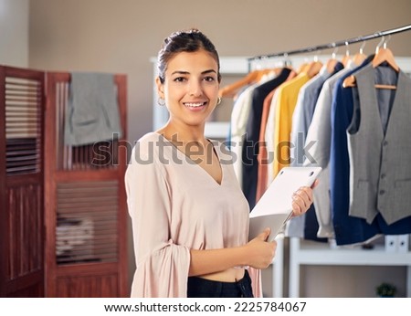 Young Modern Confident Indian Asian Entrepreneur woman or female professional fashion stylist is holding a notebook or a laptop in hand in boutique looking at camera. Self-employment, Startup concept Royalty-Free Stock Photo #2225784067