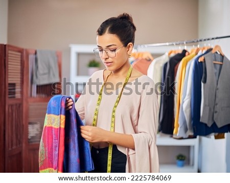 Modern attractive Young Indian Asian woman or female professional fashion designer is holding a colorful piece of cloth in a store or garments boutique workshop. Concept of self-employment. Royalty-Free Stock Photo #2225784069