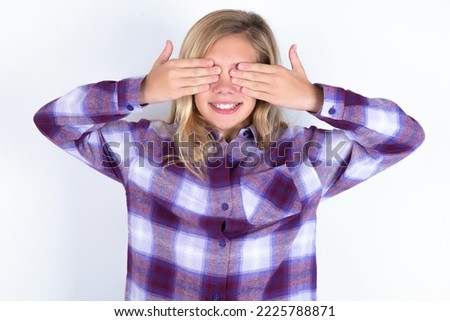 caucasian teen girl wearing plaid purple shirt over white wall covering eyes with hands smiling cheerful and funny. Blind concept.